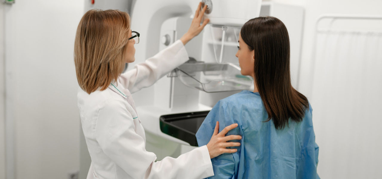 doctor readies mammogram machine for female patient for preventative care exam