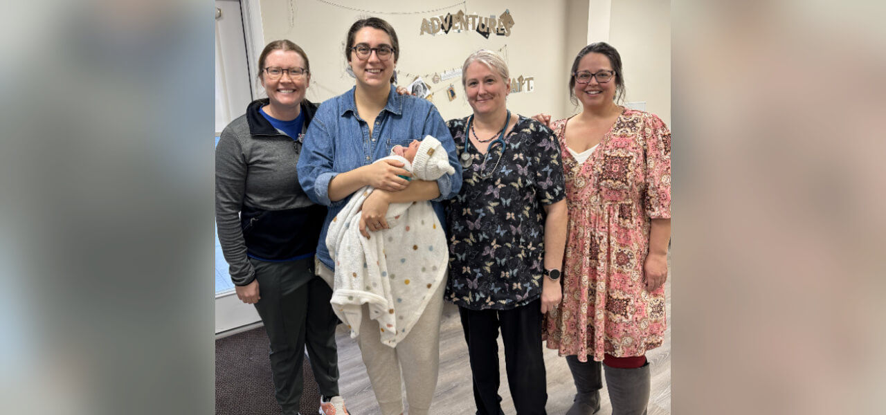 Three women standing with a mother and her new baby