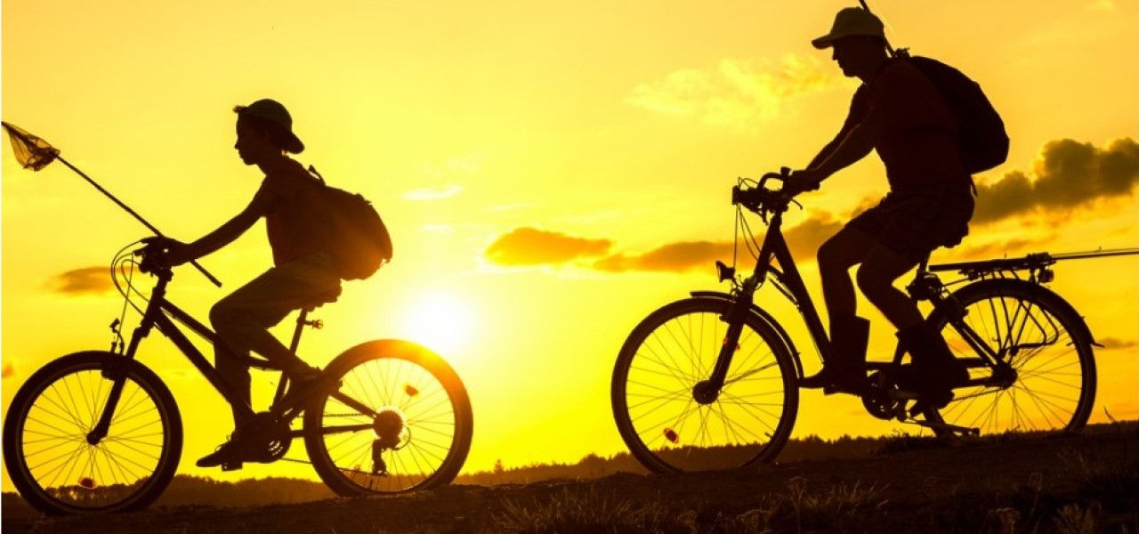 Father and son riding bikes as the sun rises