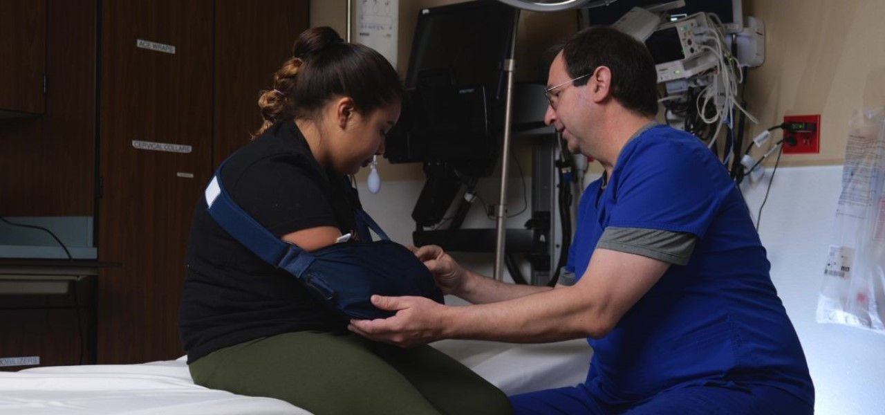 Caregiver helping patient with arm sling
